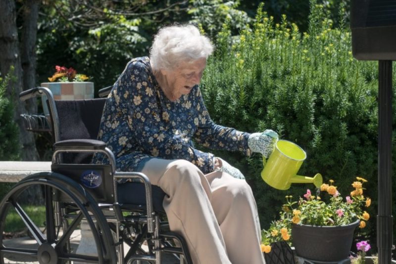 A Lexington resident watering flowers outside in the community garden.