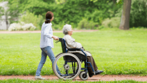 a woman carrying an older woman in a wheelchair