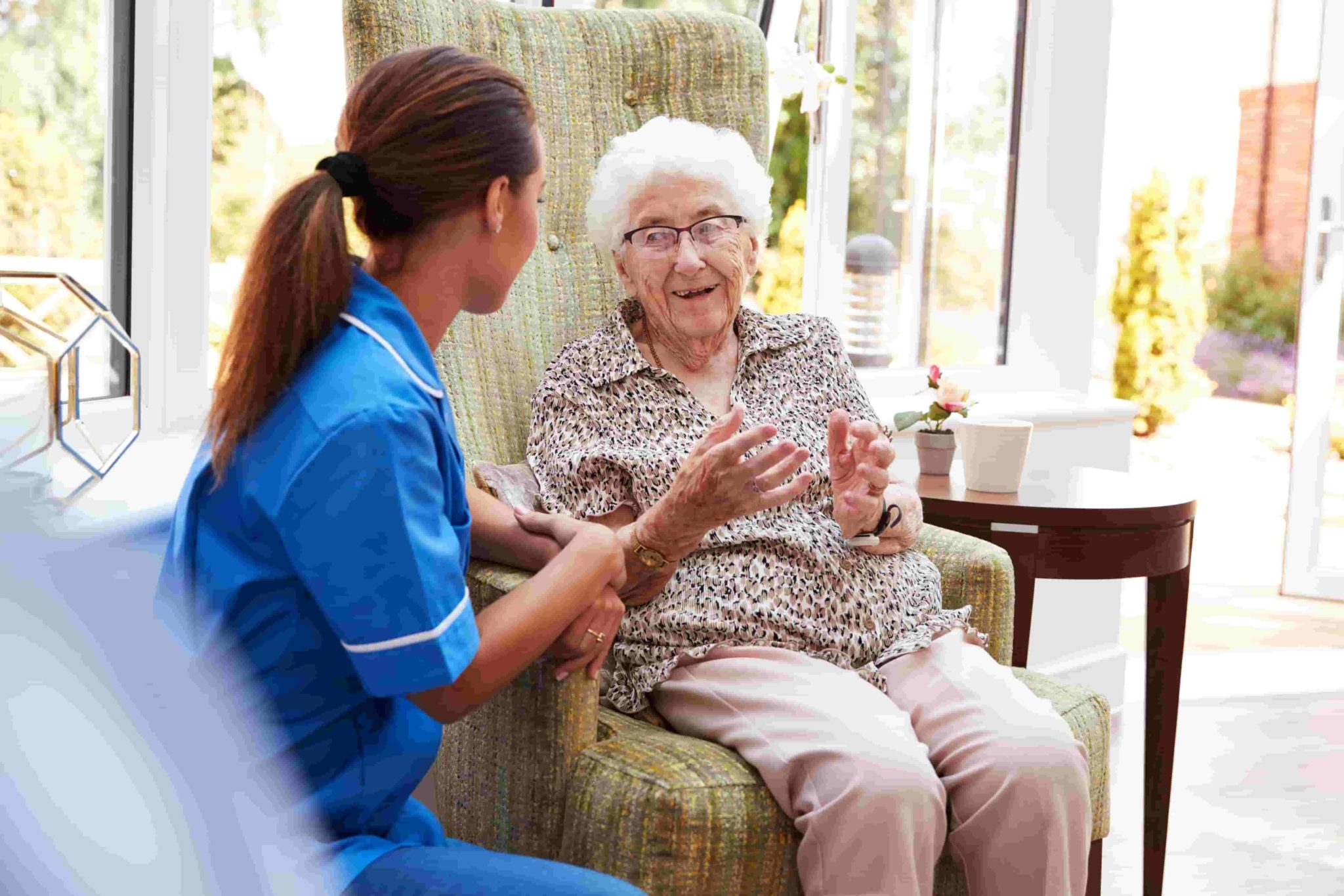 Senior woman having a conversation with a caregiver in an assisted living community.