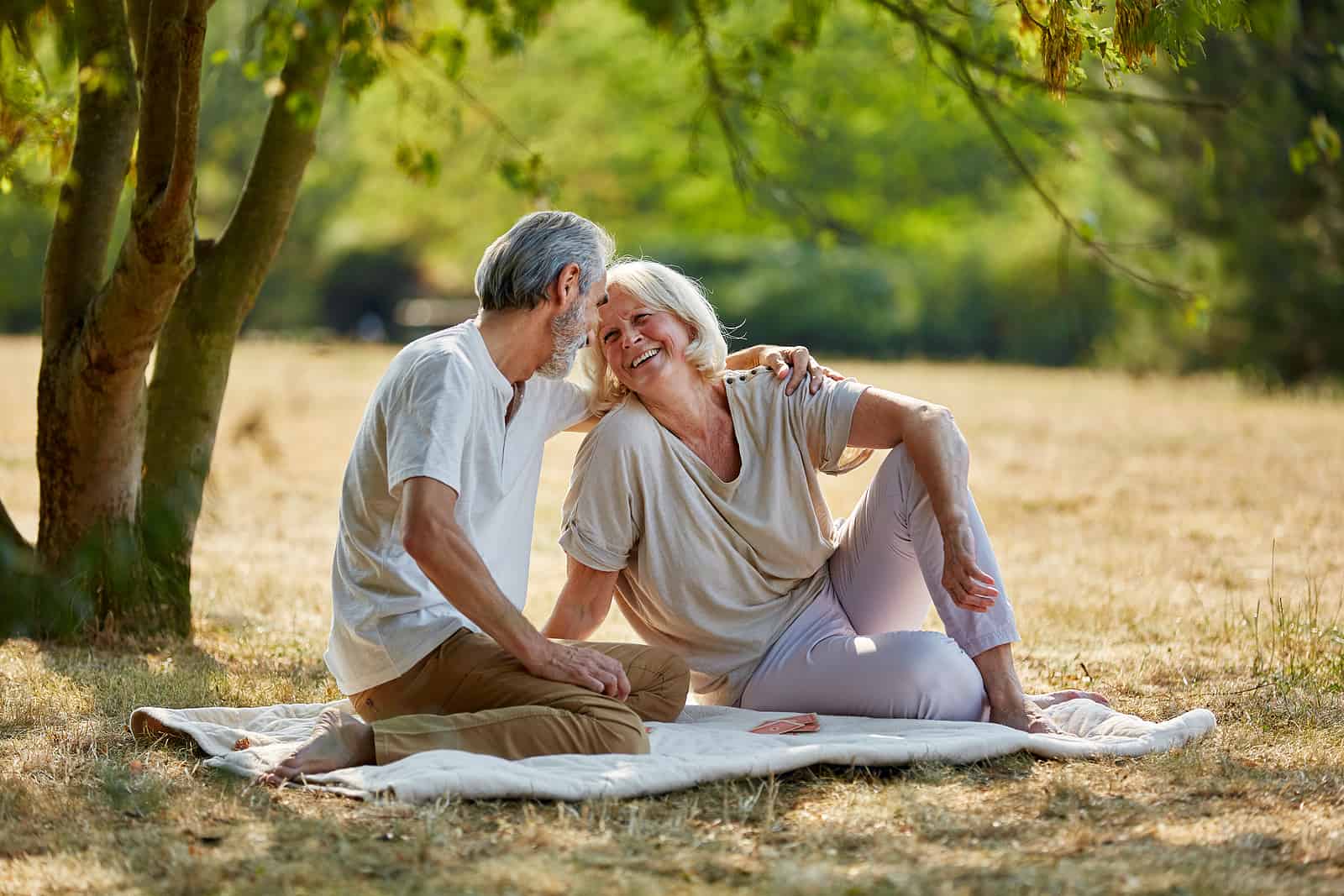 Happy senior couple enjoying a picnic outside during the summer.