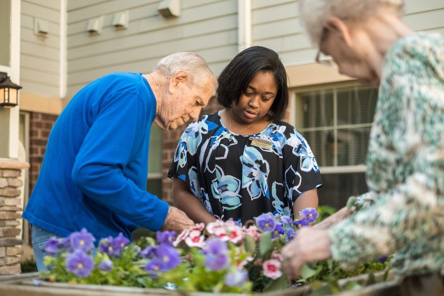 Heritage Senior Living team member and residents planting flowers.