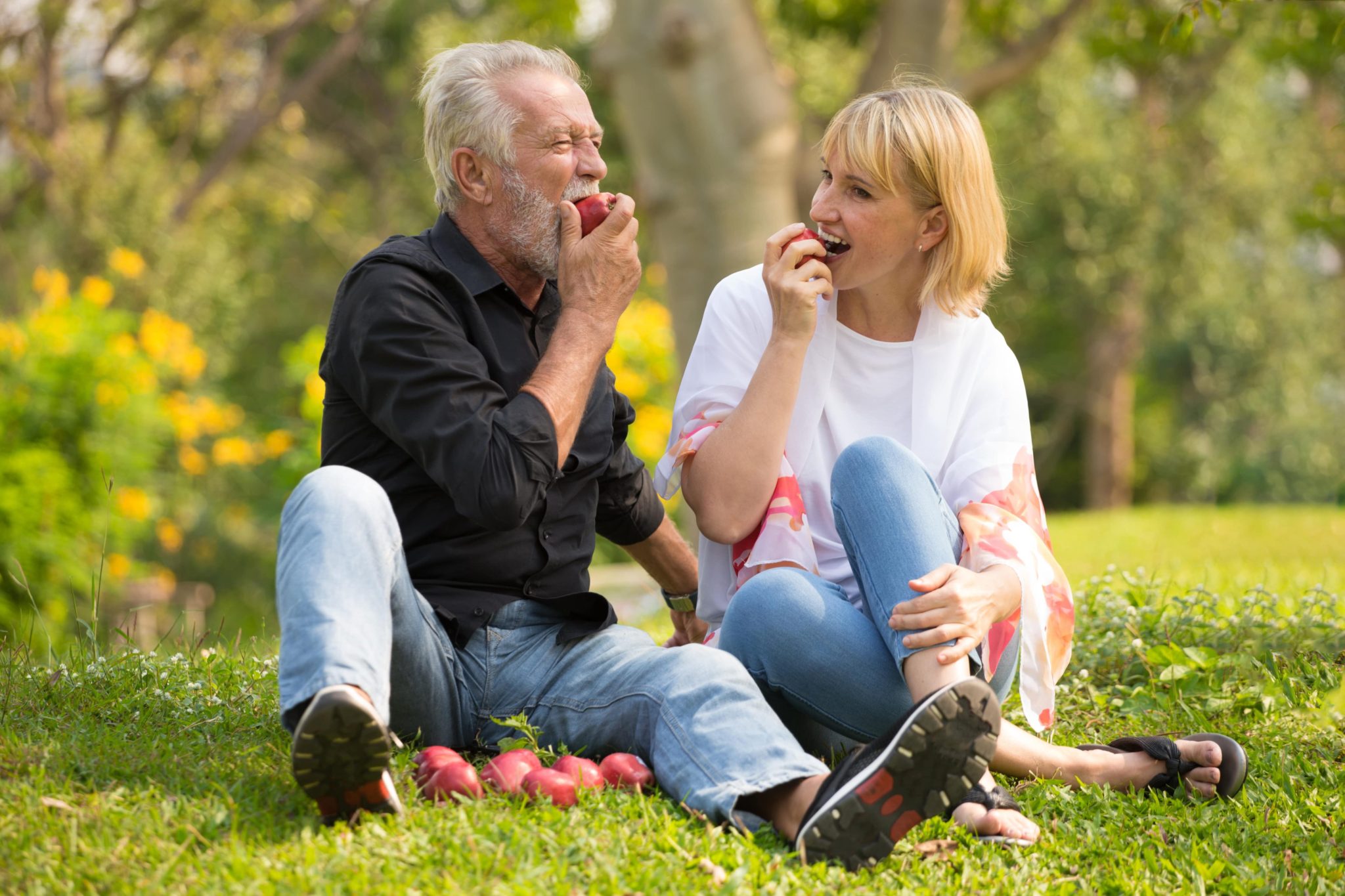 Senior couple enjoying summer foods during a picnic in the park.