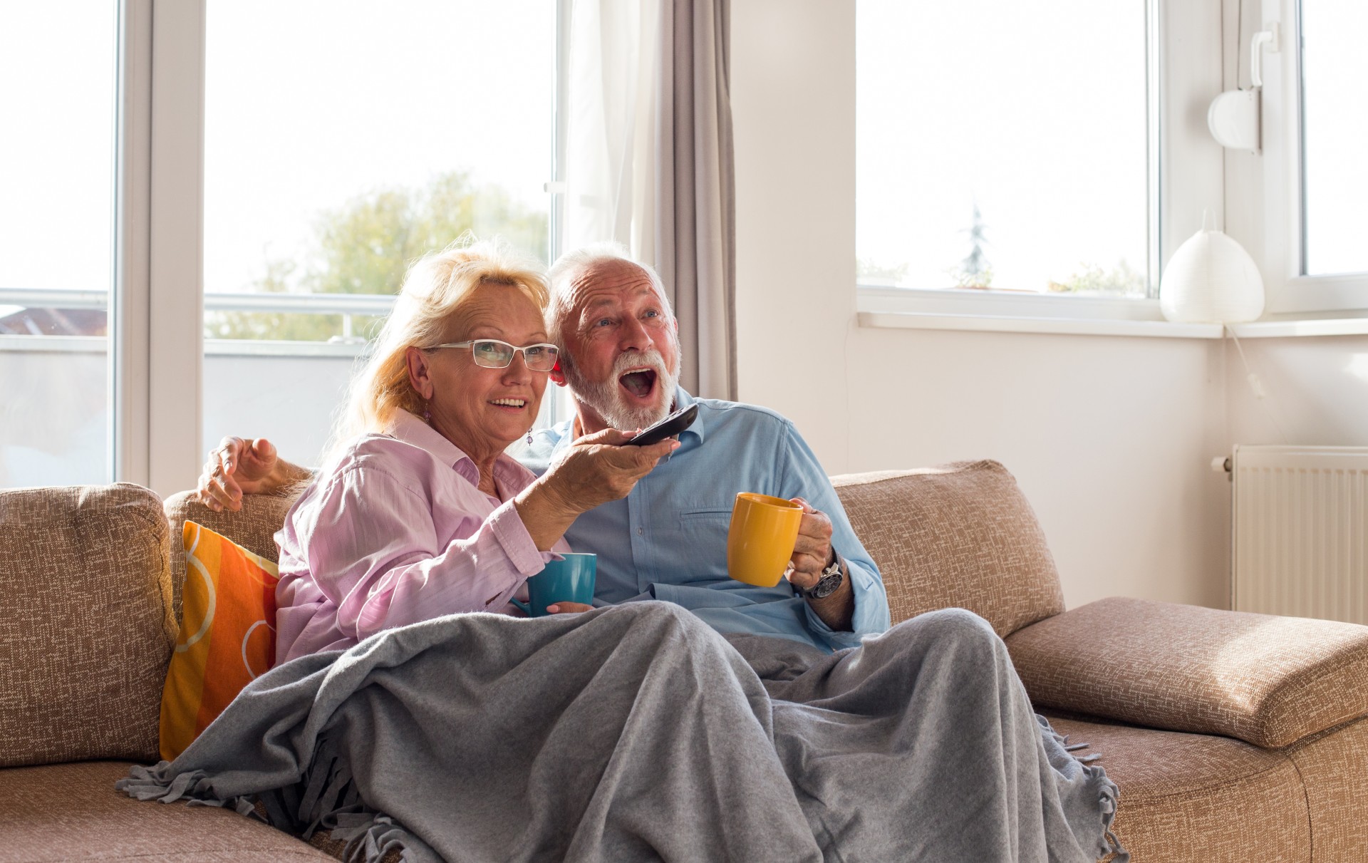 Happy senior couple watching TV at home