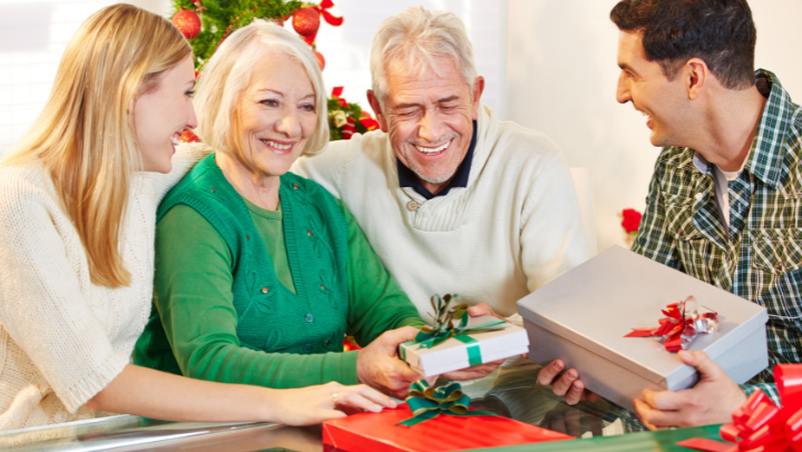an elderly couple with their children opening Christmas presents 