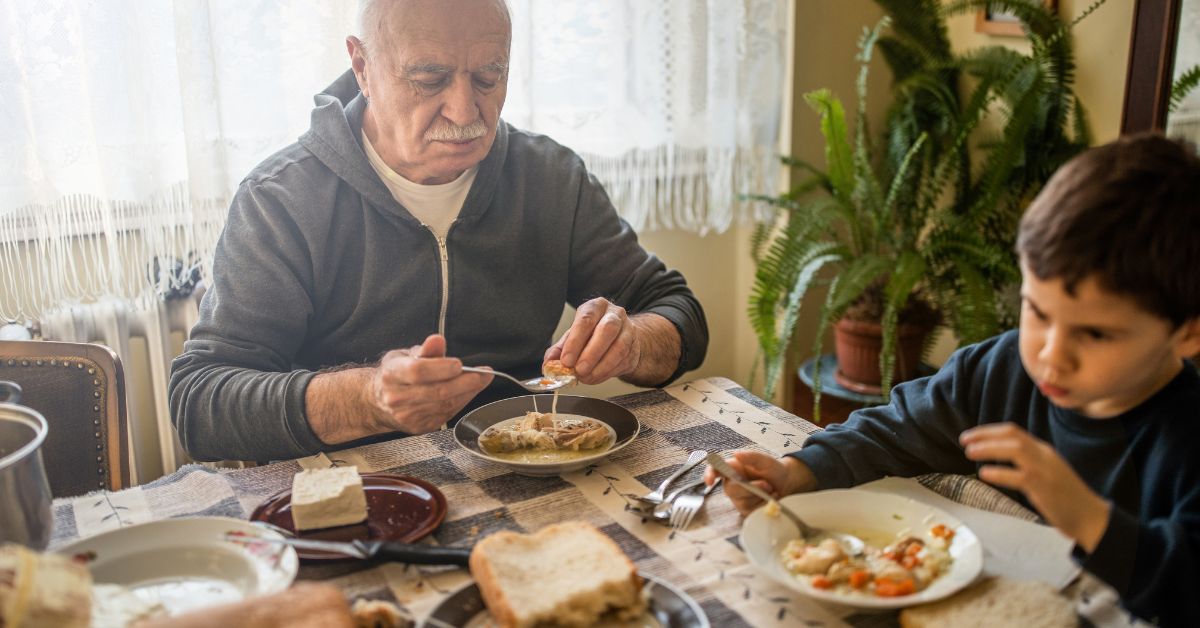 a senior man sharing breakfast with his grandson at memory care