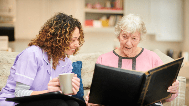 a senior lady watching a photo album with her caregiver