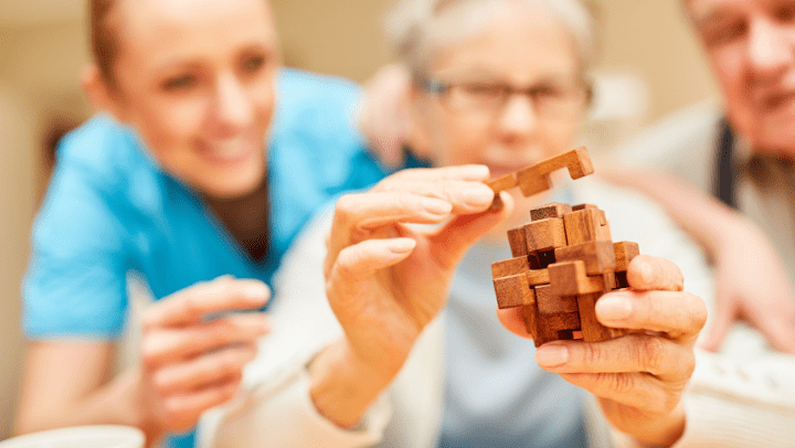 a nurse helping an elderly woman put together a puzzle