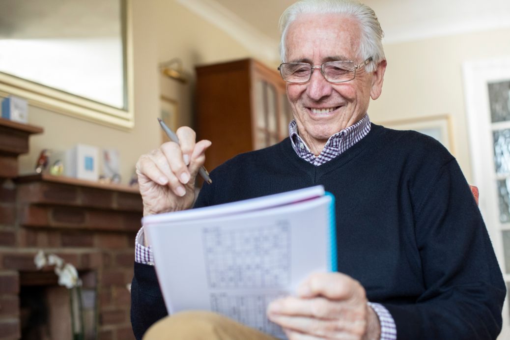 Senior male doing a crossword puzzle to promote brain health.