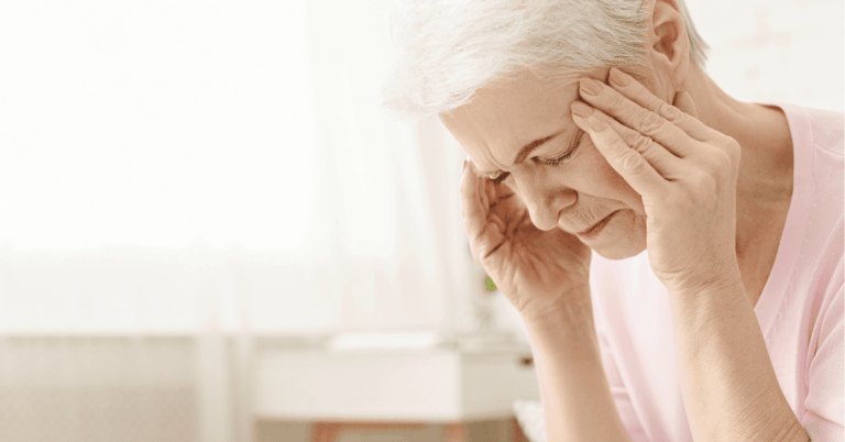 An senior woman holding her head in her hands needs help from a memory care community