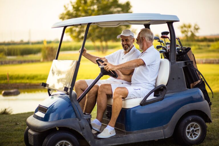 Two senior friends riding in a golf cart