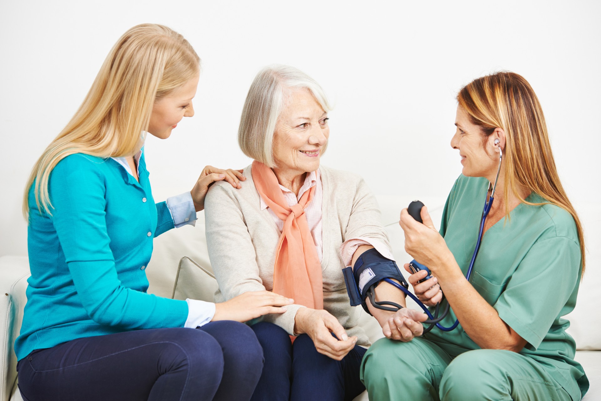 Senior woman with her daughter and nurse doing blood pressure monitoring